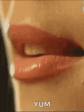 a close up of a woman 's mouth with red lipstick and the words yum written on the bottom .