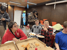 a group of young men are eating pizza in a room with a vending machine that says free pizza