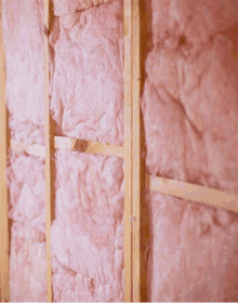 a wall with pink insulation on it and wooden beams