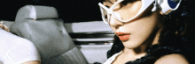 a woman wearing sunglasses and headphones sits in a car