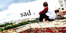 a boy sits on the edge of a brick wall with the word sad behind him