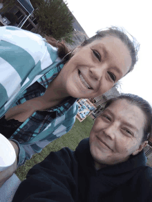 two women are posing for a picture and one of them is wearing a plaid shirt