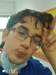 a boy wearing glasses and a mask takes a selfie with a redmi 7 ai dual camera