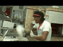 a man wearing a red headband and a white shirt with the word italia on it is preparing food in a kitchen