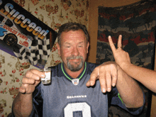 a man wearing a seahawks jersey is holding a shot glass