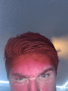 a close up of a man 's face with red hair and blue eyes