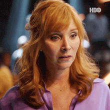 a woman with red hair is wearing a purple shirt with hbo written on the bottom right
