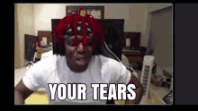 a man with red hair is sitting in front of a computer with the words `` your tears '' written on his face .