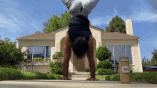 a man is doing a handstand in front of a house with a can of mock coffee in the foreground