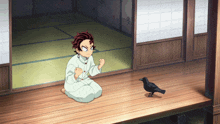 a boy is kneeling down next to a bird on a porch