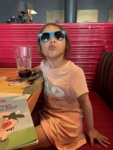 a little girl wearing sunglasses is sitting at a table with a menu on it that says ' molly ' on it