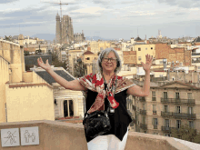 a woman stands on a balcony with her arms outstretched in front of a cityscape