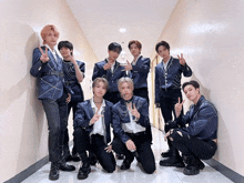 a group of young men are posing for a picture in a hallway and giving the peace sign