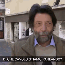 a man with a beard is standing in front of a building with the words di che cavolo stiamo parlando