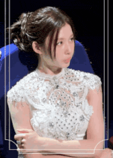 a woman in a white dress is sitting in a blue chair with her arms crossed