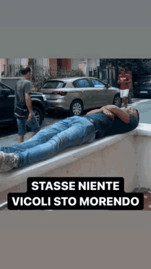 a man laying on a wall with the words tasse niente vicoli sto morendo