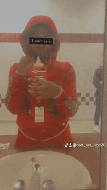 a person in a red hoodie taking a selfie in front of a mirror that says i don 't care on it