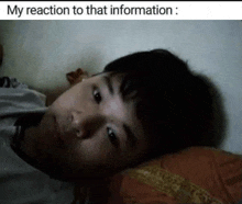 a young boy is laying on a bed with his head on a pillow and looking at the camera .