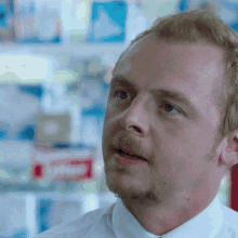 a close up of a man 's face with a shelf in the background that says ' shaving cream ' on it