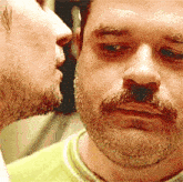 a man with a beard is kissing another man 's cheek
