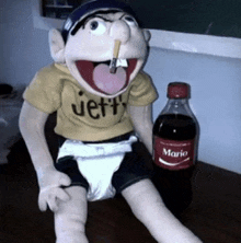 a puppet with a cigarette in his mouth is next to a bottle of mario