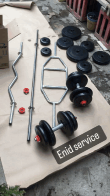 a bunch of dumbbells and barbells are laying on a piece of cardboard with the words enid service written on it