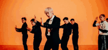 a group of men are dancing in front of an orange background .