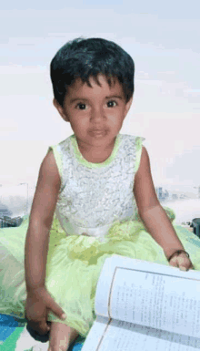 a little girl is sitting on a bed with a book