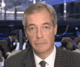 a man in a suit and tie is looking at the camera with a serious look on his face