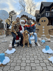 two men and a dog pose for a picture with santa claus and a gingerbread man