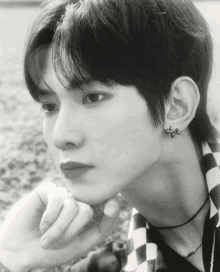 a black and white photo of a young man wearing a necklace and earrings