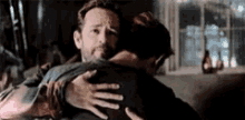 two men are hugging each other in a living room .