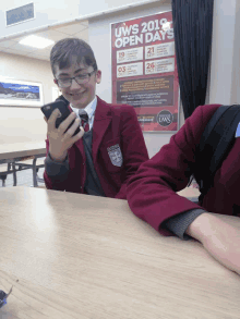 a boy is looking at his phone in front of a sign that says uws open days