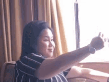 a woman is taking a selfie in front of a window while sitting on a couch .