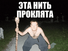 a shirtless man holding a cane with a skull on it in front of a graveyard