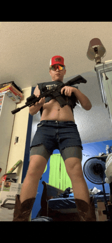 a man wearing shorts and cowboy boots holds a rifle