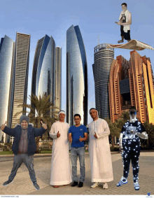 a group of men are posing for a picture with a man flying on a carpet in the background