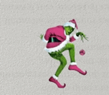 the grinch is wearing a santa claus outfit and holding a christmas ball .