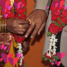 a man is putting a ring on a woman 's finger surrounded by hearts