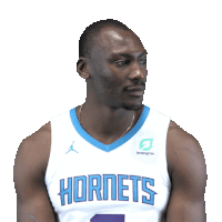 a basketball player wearing a hornets jersey looks to the side