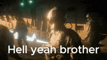 a man in a helmet stands in front of a sign that reads hell yeah brother