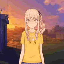 a blonde anime girl wearing a yellow t-shirt is standing in front of a sunset .