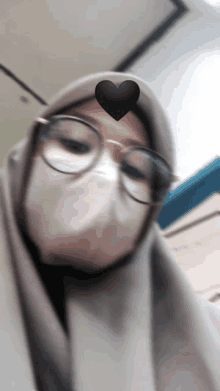 a woman wearing glasses and a face mask has a heart on her head