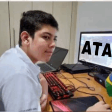 a young man is sitting in front of a computer with the word ata written on the screen