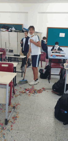 a boy wearing a mask is standing in a messy classroom