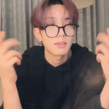 a young man wearing glasses and a black shirt is making a face .