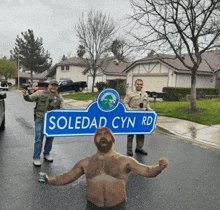 a shirtless man holds up a sign that says soledad cyn rd