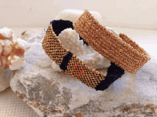 two bracelets are sitting on a rock next to a shell