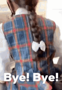 a little girl in a plaid dress with a braid and a bow in her hair is saying bye ! bye !