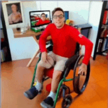 a man in a red shirt is sitting in a wheelchair in a living room .